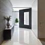 Ein moderner Flur mit glänzendem Marmorboden, weißen Wänden, schwarzer Tür und minimalistischer Dekoration.